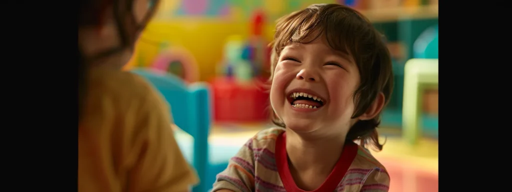 a young child smiling brightly while receiving praise from a caregiver in a colorful daycare setting.